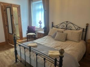 a bedroom with a bed and a chair and a window at Rose Cottage in Greencastle