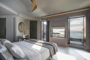 a bedroom with a large bed and a large window at Kivotos Santorini - Preferred Hotels & Resorts in Imerovigli