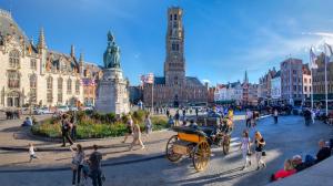 a city with a horse drawn carriage in the street at Golden Tulip Hotel de’ Medici in Bruges