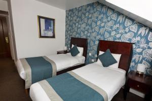 two beds in a hotel room with blue and white wallpaper at Basingstoke Hotel in Hook
