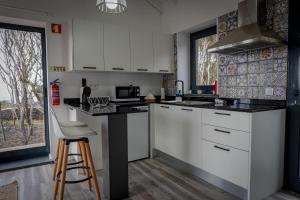 a kitchen with white cabinets and a counter with a stool at AL Adega do Calcetas in Cais do Mourato