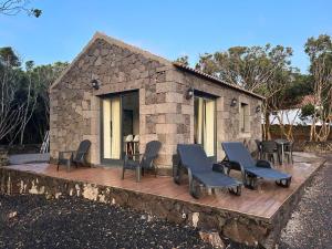 a stone house with chairs and a deck at AL Adega do Calcetas in Cais do Mourato