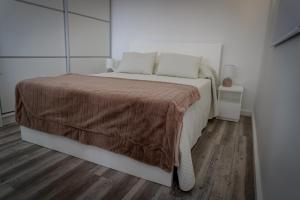 a white bedroom with a bed with a brown blanket at AL Adega do Calcetas in Cais do Mourato
