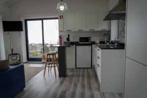 a kitchen with white cabinets and a table with a stool at AL Adega do Calcetas in Cais do Mourato +16 photos
