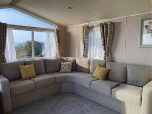 a living room with a large couch with yellow pillows at Hendre Coed Isaf Caravan Park in Barmouth