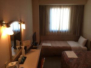 a hotel room with a bed and a desk with a mirror at Hotel Crown Hills Kanazawa in Kanazawa