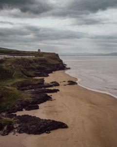 a beach with rocks and the ocean on a cloudy day at Railway Sleeper Hostel in Castlerock