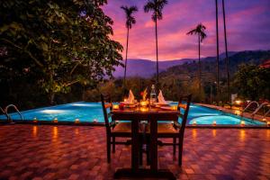 a table with chairs next to a swimming pool at Hill Crest Resort - Coorg in Madikeri