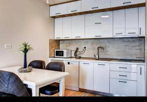 a kitchen with white cabinets and a table with chairs at Mar de Lux in Petrovac na Moru