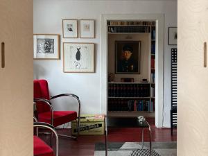 a living room with red chairs and a book shelf with books at Bed & Breakfast Bep - Klein aber fein in Naumburg