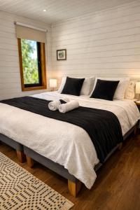 a bedroom with a large bed with two pillows at Cabañas Alto del Bosque in Coñaripe +35 photos