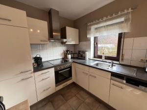 a kitchen with white cabinets and a sink and a window at Ferienwohnung Zöll-Wedra in Traben-Trarbach