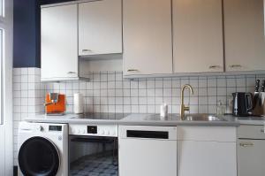 a white kitchen with a sink and a dishwasher at ReLiving - Historic City Apartment in Lucerne