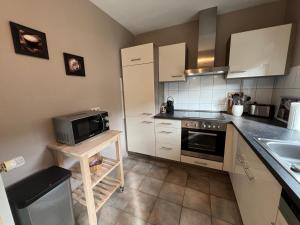 a kitchen with white cabinets and a sink and a microwave at Ferienwohnung Zöll-Wedra in Traben-Trarbach +3 photos