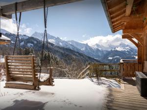 a swing on a porch in the snow at Chalet Sivara - OVO Network in Manigod