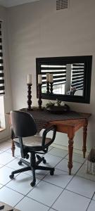 a desk with a chair in front of a mirror at Meltz Inn in Klerksdorp