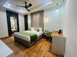 a bedroom with a bed and a desk and a ceiling fan at Red Leaf Hisar in Hisār +35 photos