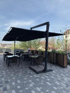 a patio with tables and chairs under a black umbrella at Graf Hotel in Shymkent