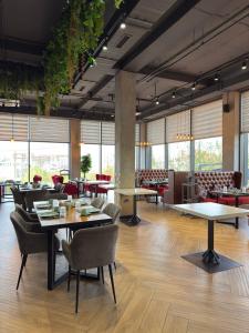a restaurant with tables and chairs and windows at Graf Hotel in Shymkent