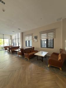 a waiting room with couches and tables and windows at Graf Hotel in Shymkent