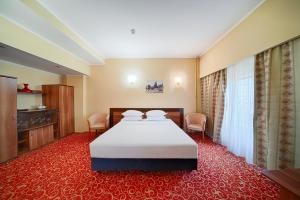 a hotel room with a bed and a red carpet at Hotel Central in Ploieşti +64 photos