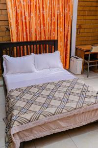 a bed in a room with an orange curtain at Fern Haven in Port Harcourt