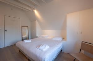 a bedroom with a large white bed with white sheets at Calm, Light-Filled Apartment with Private Balcony in Knokke-Heist