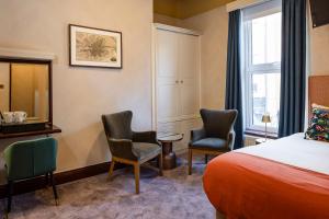 a hotel room with a bed and two chairs at O'Donoghue's in Dublin