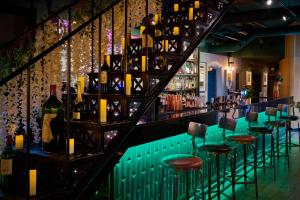 a bar with green chairs and bottles of wine at Malmaison Oxford in Oxford