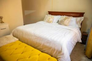 a bedroom with a large bed with white sheets and pillows at Urban Escape Apartment in Mbarara