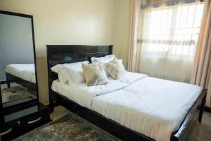 a bedroom with a bed with white sheets and a mirror at Urban Escape Apartment in Mbarara +4 photos