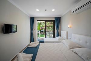 a hotel room with three beds and a television at KIYI SUITES OTEL Palamutbükü in Yakaköy