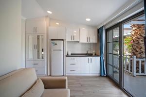 a kitchen with white cabinets and a white refrigerator at KIYI SUITES OTEL Palamutbükü in Yakaköy