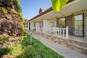 a house with a porch and a cat sitting on the sidewalk at KIYI SUITES OTEL Palamutbükü in Yakaköy