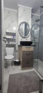 a bathroom with a toilet and a sink and a mirror at Little Escape in Brăila