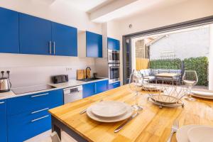 a kitchen with blue cabinets and a wooden table at La Maison de lOrb in Valras-Plage