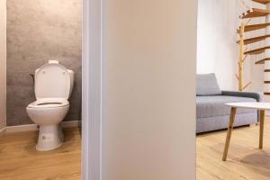 a bathroom with a toilet in a room with a couch at La Maison de lOrb in Valras-Plage