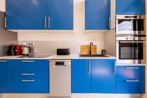 a blue kitchen with white counters and blue cabinets at La Maison de lOrb in Valras-Plage