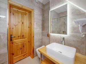 a bathroom with a white sink and a wooden door at Golden Apartments - Villa Taternik - Studio with balcony in Zakopane +32 photos