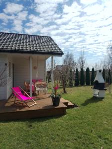 a deck with a pink chair and a grill at Las Palmas in Kołczewo