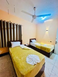 two beds in a room with a ceiling fan at Kelany Palace Hotel Aswan in Aswan