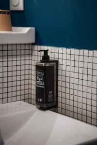 a black soap dispenser on a tiled bathroom wall at Hotel Ibis Budget Fecamp in Fécamp +39 photos