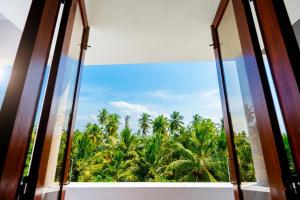 an open window with a view of palm trees at Signature Grande with swimming pool pondicherry in Pondicherry