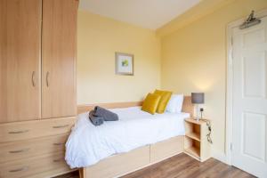 a bedroom with a bed with white sheets and yellow walls at Spacious 4-Bed Central Limerick Group Retreat in Limerick +19 photos