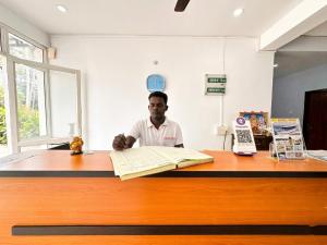 a man sitting at a desk with a book at SS Grand with swimming pool in Pondicherry +42 photos