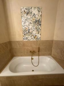 a bath tub in a bathroom with a painting on the wall at Pension "Zum Romröder Steingarten" in Romrod