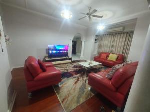 a living room with two red chairs and a flat screen tv at Peaceful Corner Stay in Durban