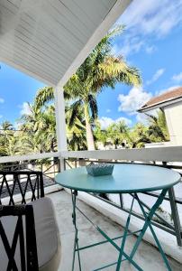 a blue table on a balcony with palm trees at Beach House Koko Apartment in Grand-Baie