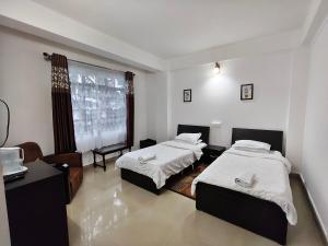 a bedroom with two beds and a window at Lashisha in Shillong