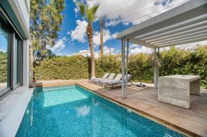 a swimming pool with two chairs next to a house at DownTown Villa 2 in Paphos